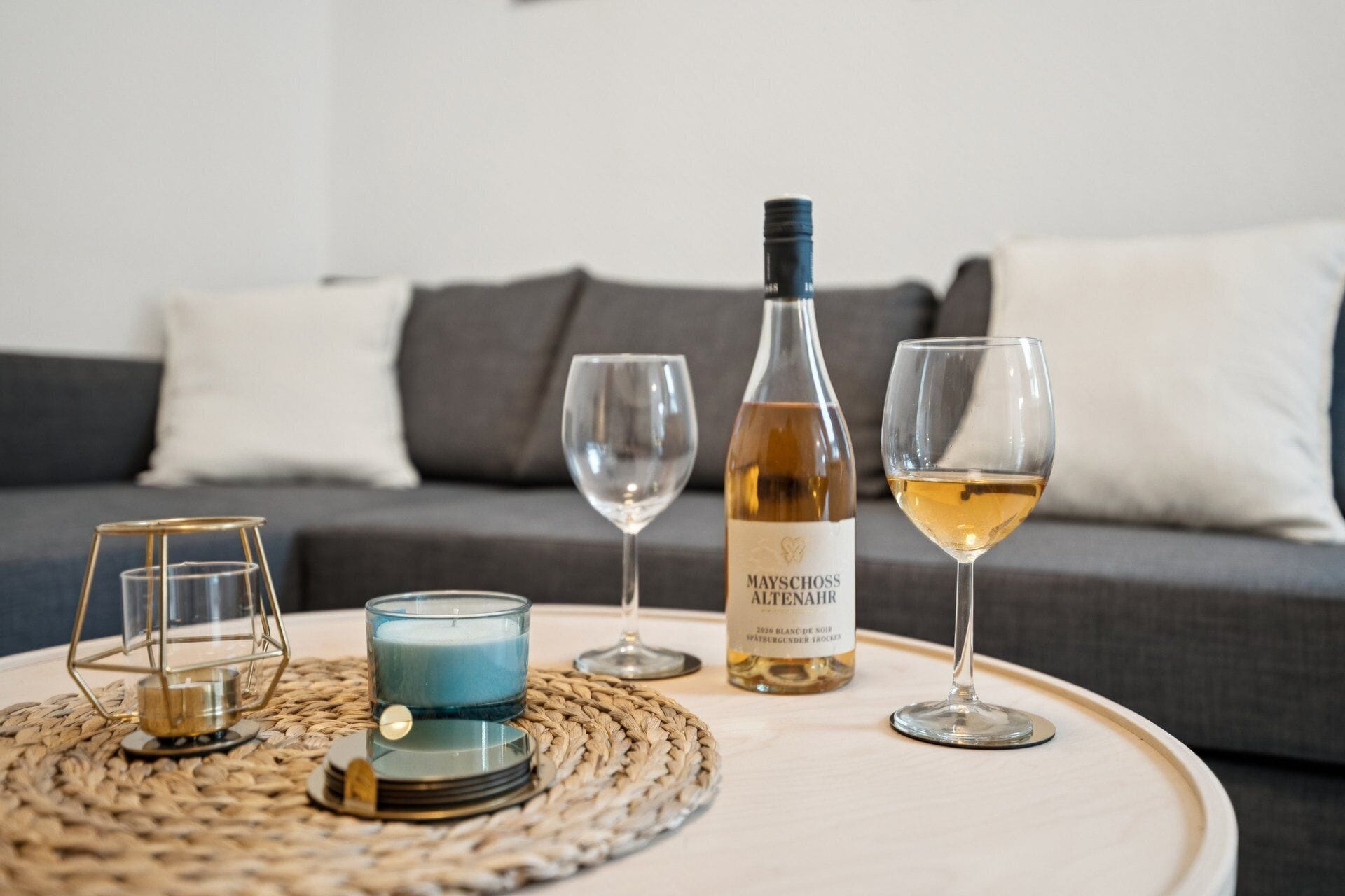 Una mesa redonda con una botella de vino, dos copas, una vela y un candelabro decorativo.