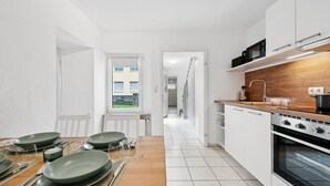 A modern kitchen with white cabinets, a wooden countertop, and a view of a building through a window. - Haven of peace for people & dogs with terrace (Andernach)