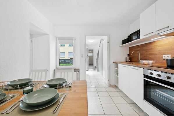 A modern kitchen with white cabinets, a wooden countertop, and a view of a building through a window. - Haven of peace for people & dogs with terrace (Andernach)
