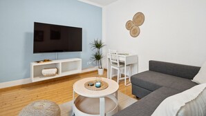 A modern living room with a flat-screen TV, a grey sofa, a white dining table, and a round coffee table. - Haven of peace for people & dogs with terrace (Andernach)