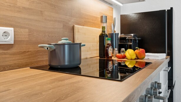 A modern kitchen with a wooden countertop, a stove, a pot, and various kitchen items. - Haven of peace for people & dogs with terrace (Andernach)