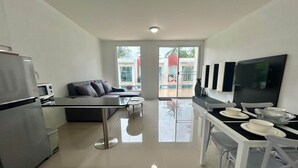 A modern kitchen with a refrigerator, microwave, and dining area with a table and chairs. - Modern Townhouse | Condo in Sam Roi Yot (Sam Roi Yot)