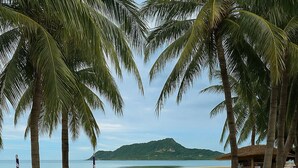 A beach with palm trees, lounge chairs, and a road with a yellow line. - Modern Townhouse | Condo in Sam Roi Yot (Sam Roi Yot)
