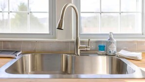 Ein Edelstahl-Spülbecken mit modernem Wasserhahn, einer Seifenspender und einer Spülbürste auf einer Holz Arbeitsplatte.