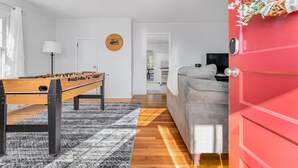 Ein modernes Wohnzimmer mit einem Kicker, einem grauen Sofa und einer roten Tür.