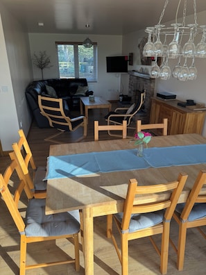 A dining area with a wooden table, chairs, a TV, and a fireplace.