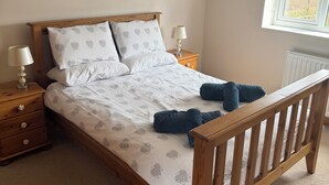 Une chambre à coucher avec un lit en bois, deux tables de chevet, une lampe, un radiateur et une fenêtre donnant sur un beau paysage.