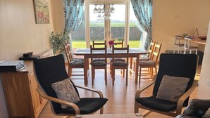 Un espace repas comprenant une table, des chaises et donnant sur l’extérieur.