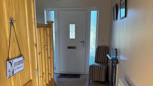 Un escalier en bois mène à une pièce où se trouvent un radiateur, une chaise à rayures et une porte avec une pancarte.