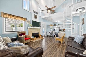 A spacious living room with a fireplace, a dining area, and a spiral staircase.