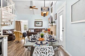 A dining area with a glass table, white chairs, and a ceiling fan. - Coastal Beach Retreat, Steps from the Sand with P (Clearwater Beach)