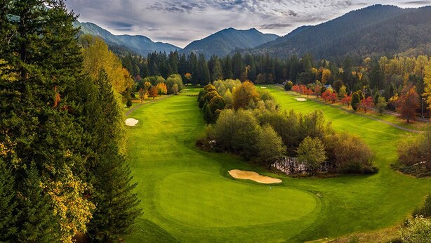 Un parcours de golf entouré d’une forêt dense et de montagnes.