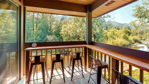 Une terrasse en bois offrant une vue sur une forêt et une rivière.