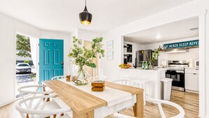 Une cuisine moderne avec des meubles blancs, une cuisinière noire et un panneau sur lequel on peut lire : « MANGER. ALLER À LA PLAGE. DORMIR. RÉPÉTER. »
