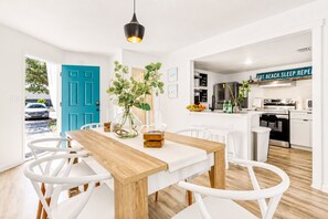 Eine moderne Küche mit weißen Schränken, einem schwarzen Herd und einem Schild mit der Aufschrift 'EAT. BEACH. SLEEP. REPEAT.'