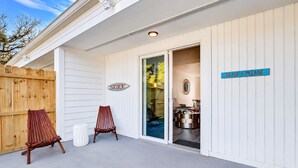 Un espace extérieur abrité, délimité par une clôture en bois, avec deux chaises en bois et un panneau indiquant le mot « SURF ».
