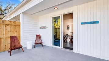 Un espace extérieur abrité, délimité par une clôture en bois, avec deux chaises en bois et un panneau indiquant le mot « SURF ».
