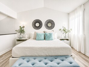 Ein modernes Schlafzimmer mit einem großen Bett, zwei Nachttischen und einer Bank.