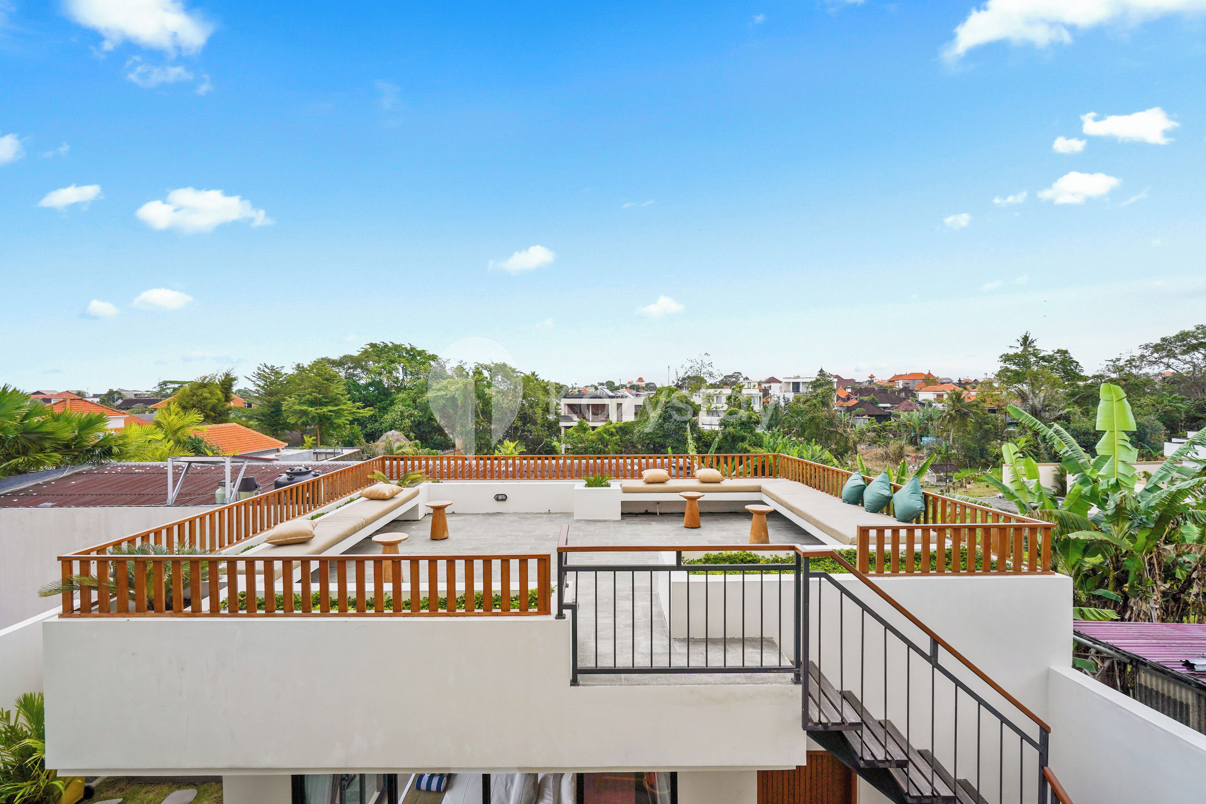 A rooftop terrace with a white railing, seating area, and a staircase leading down.