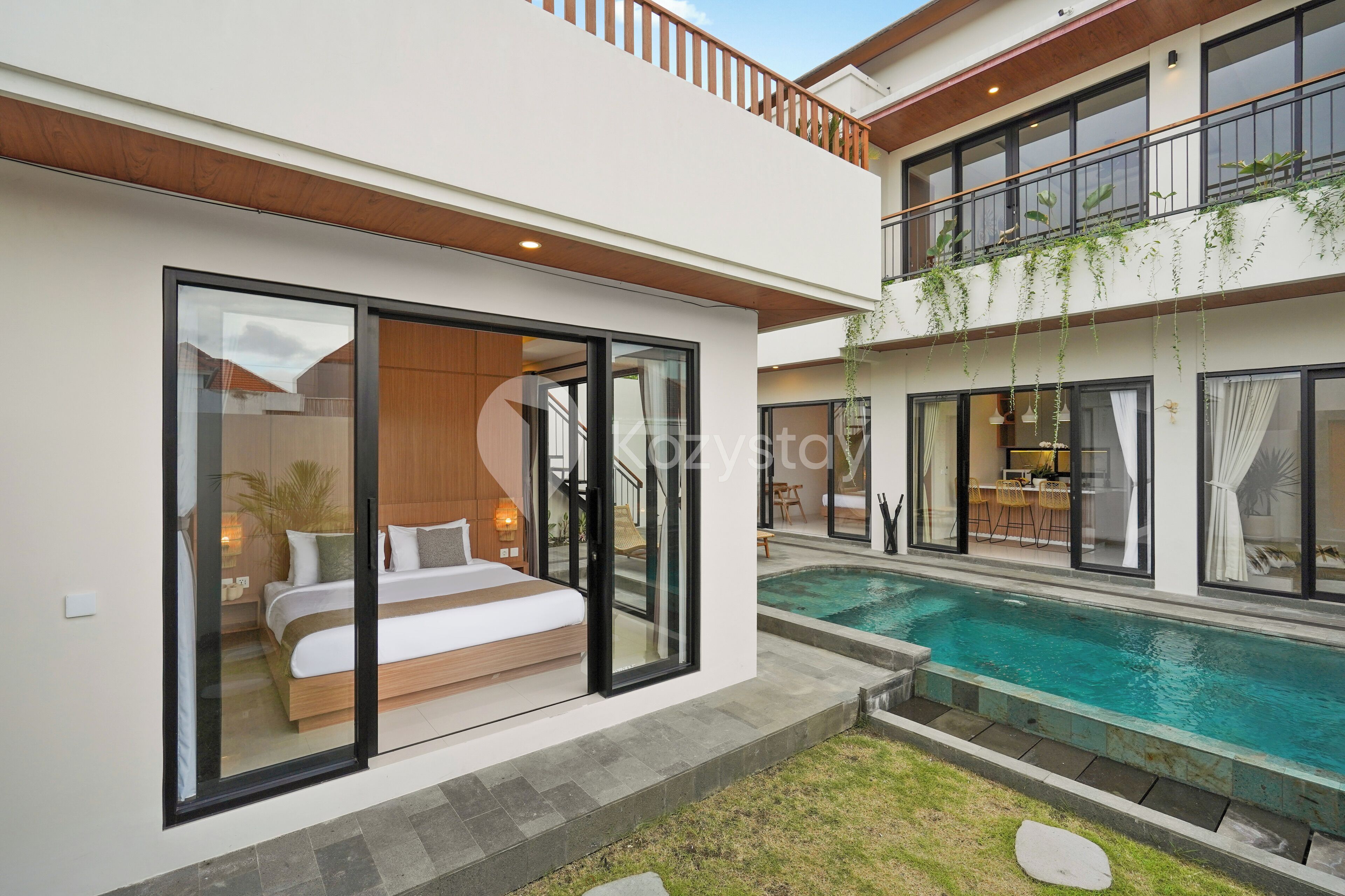 A modern two-story house with a glass-enclosed bedroom, a balcony with plants, and a swimming pool.