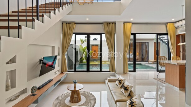 Una sala de estar moderna con una escalera, un televisor, un sofá, una mesa de centro y vistas a una piscina al aire libre.