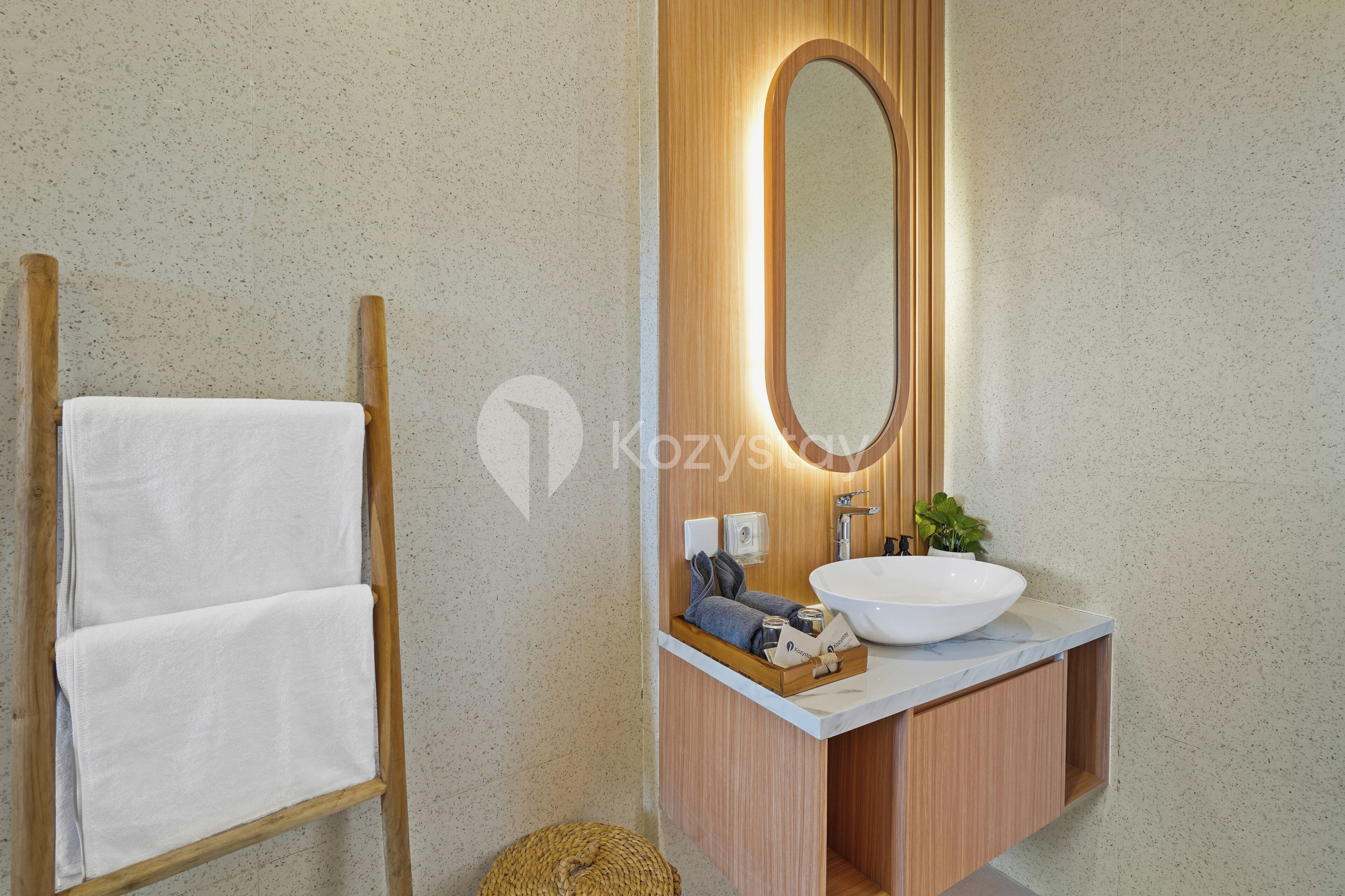 A bathroom with a wooden vanity, a large oval mirror, and a white sink.