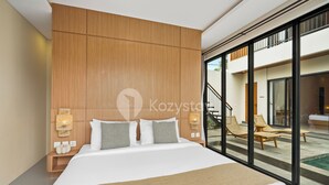 Habitación de hotel moderna con una cama grande, cabecero de madera, lámparas de noche y vistas al área de la piscina exterior.