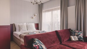 Een moderne slaapkamer met een bed, een rode bank en een groot raam met gordijnen.