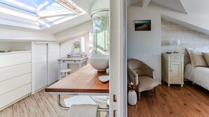 Una habitación compacta y bien iluminada con tragaluces, una mesa de comedor de madera, una cama y un armario pequeño.