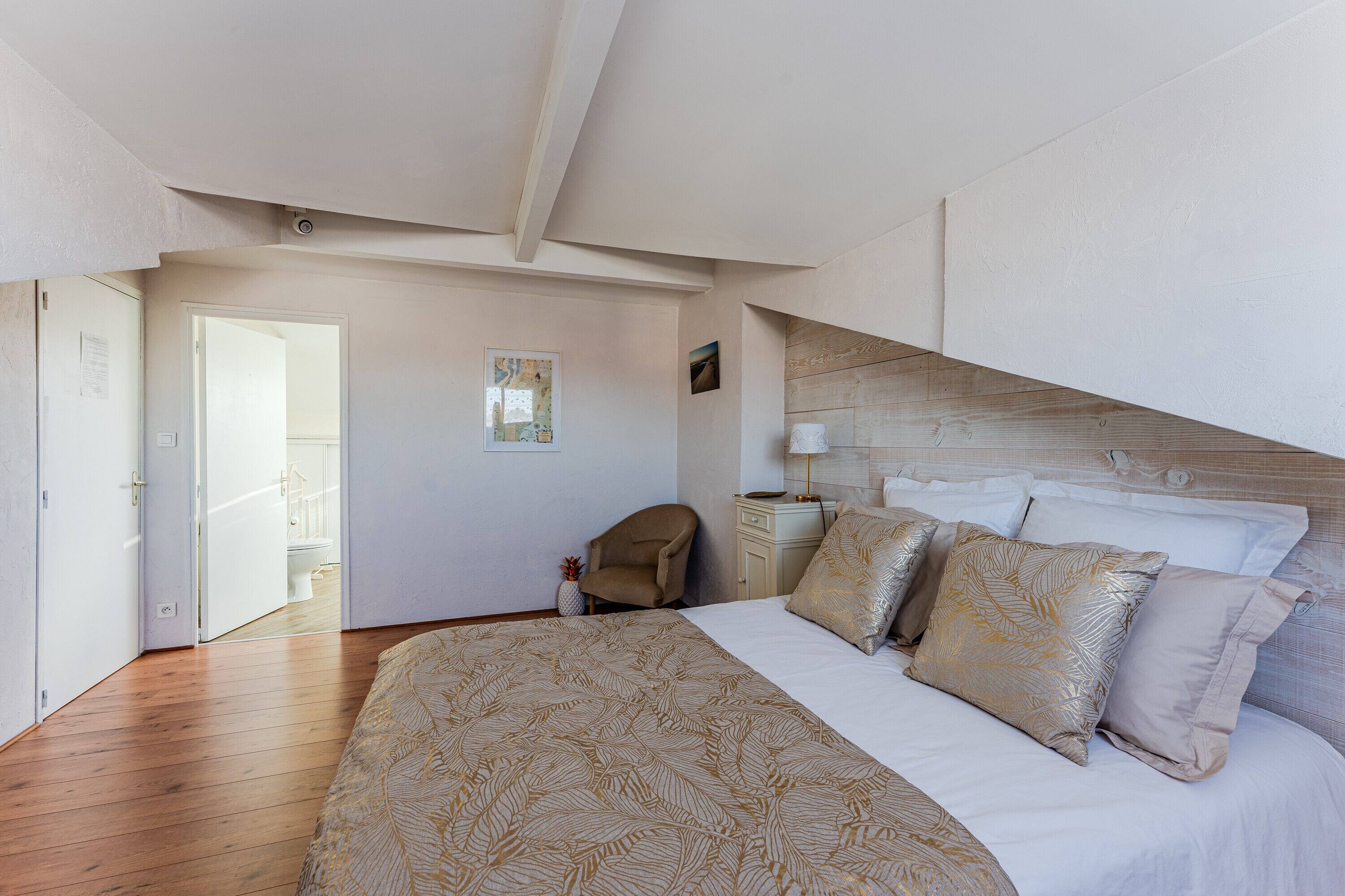 Une chambre à coucher avec un grand lit, une table de chevet, une chaise et une porte donnant sur une salle de bain.