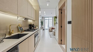 Eine moderne Küche mit einem schwarzen Spülbecken, Edelstahlgeräten und einer weißen Arbeitsplatte.