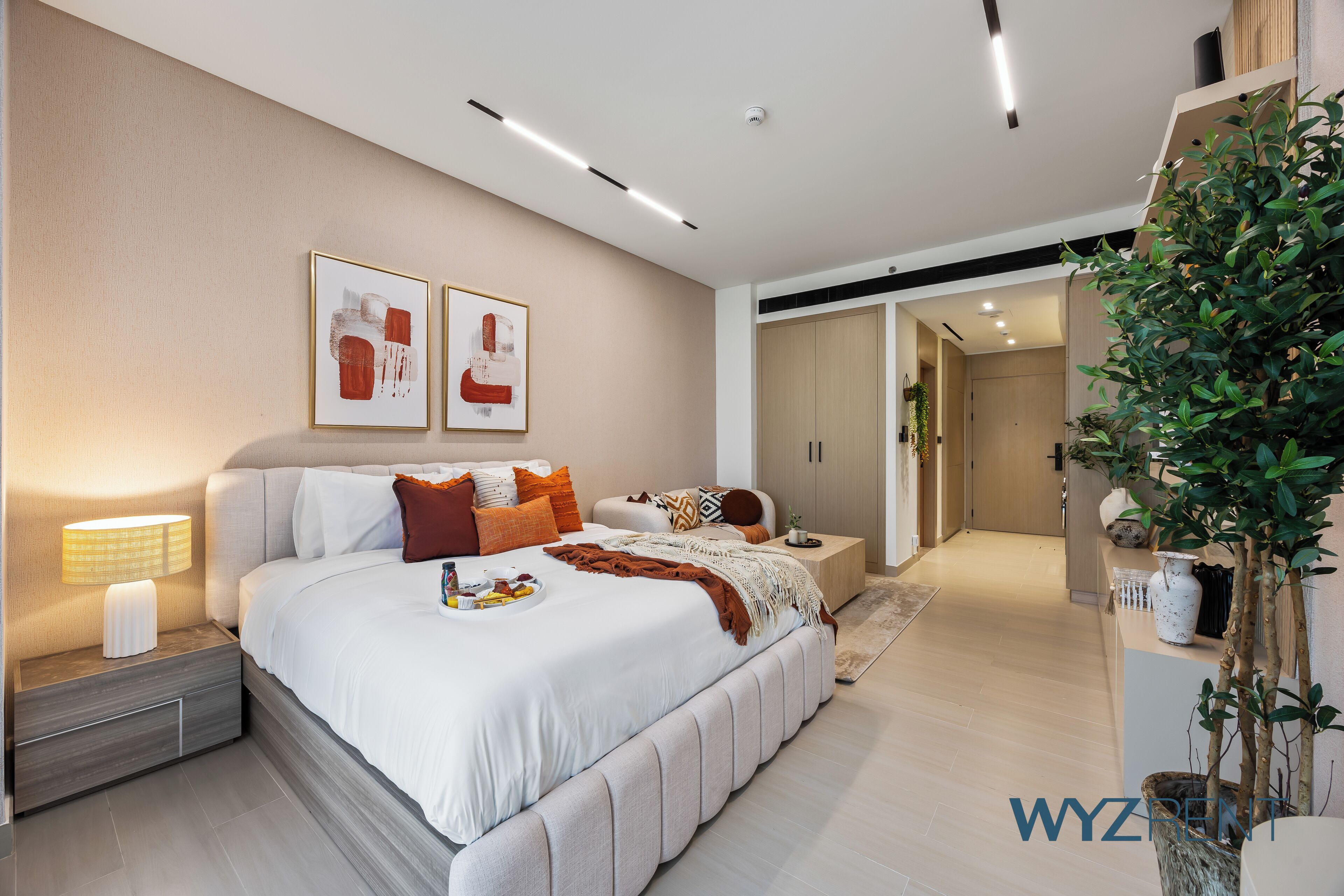 A modern bedroom with a large bed, bedside tables, a nightstand, a bedside lamp, and a wall-mounted artwork.