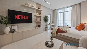 Ein modernes Wohnzimmer mit einem großen Flachbildfernseher, der 'NETFLIX' anzeigt, einem Holz-TV-Schrank, einer Couch, einem Couchtisch und einem großen Fenster.