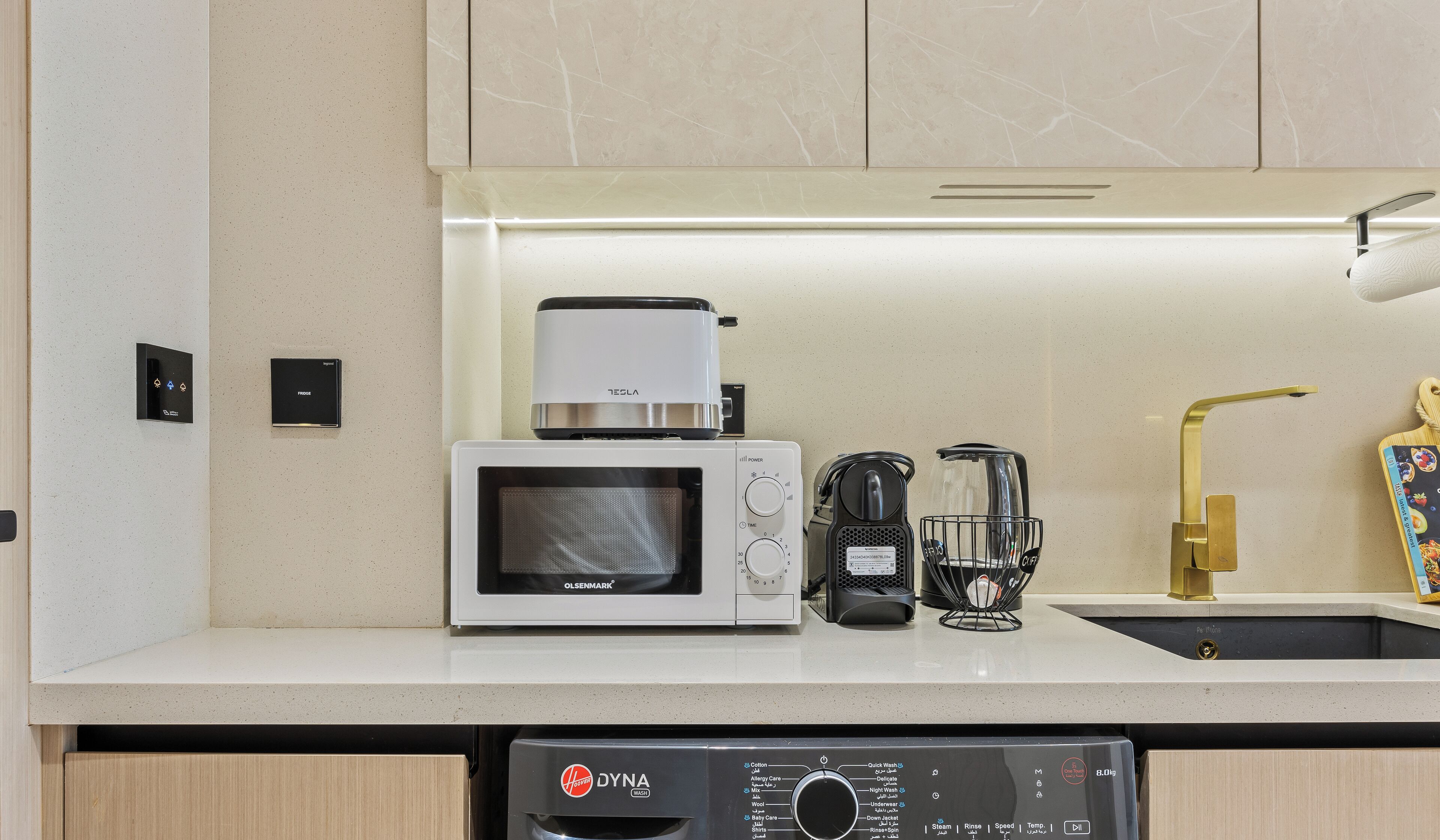 Eine moderne Küche mit Mikrowelle, Kaffeemaschine und Geschirrspüler.