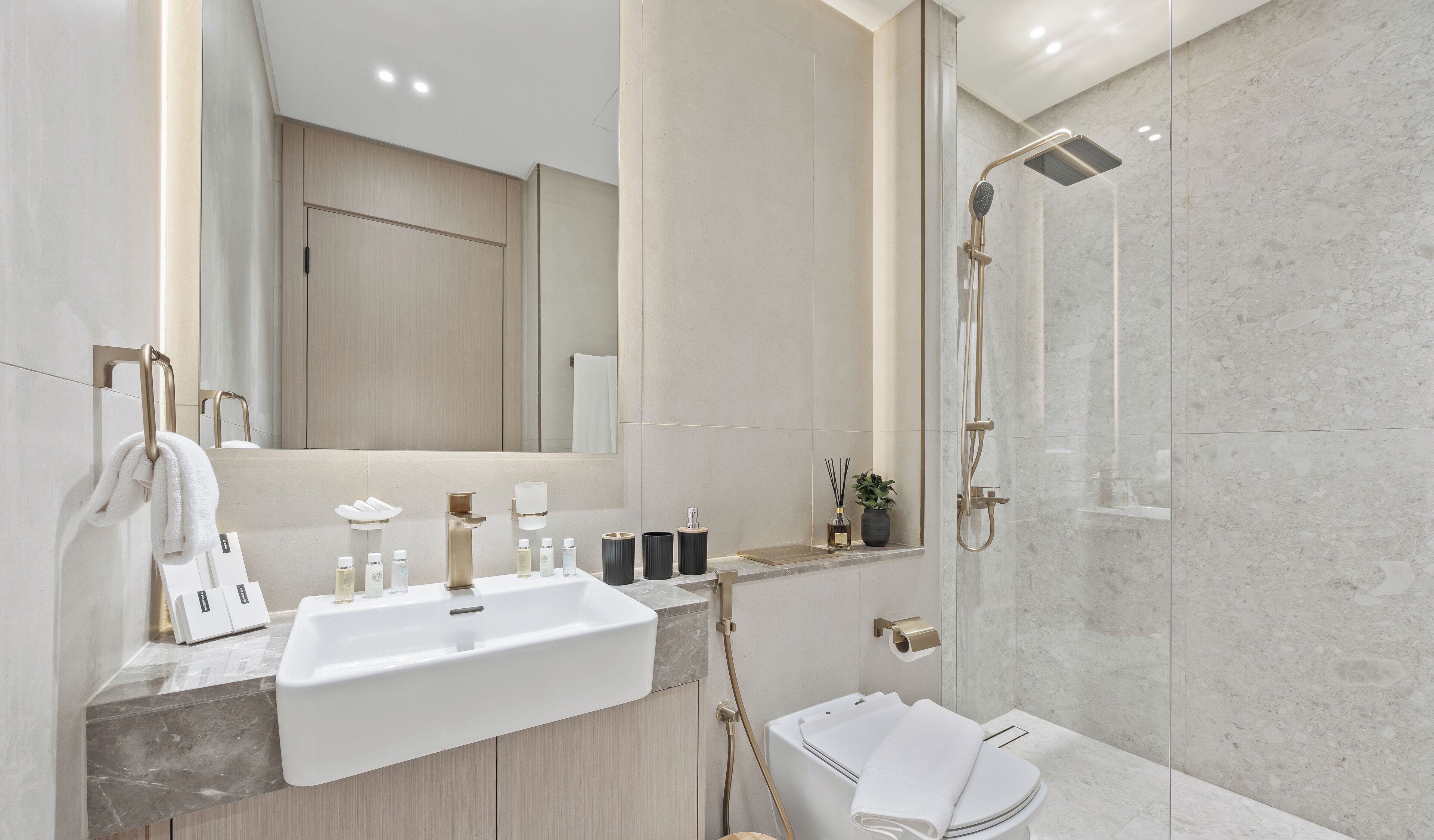 A modern bathroom with a large mirror, a sink, a shower, and a toilet.