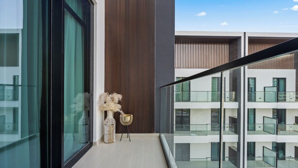 Eine moderne Wohnung mit großen Fenstern, einem Balkon und Blick auf andere Gebäude.