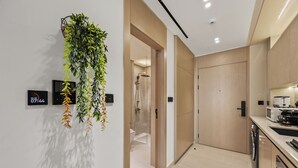 Ein modernes Badezimmer mit Dusche, Toilette und Waschbecken. Eine Wandpflanze und eine digitale Uhr sind ebenfalls vorhanden.