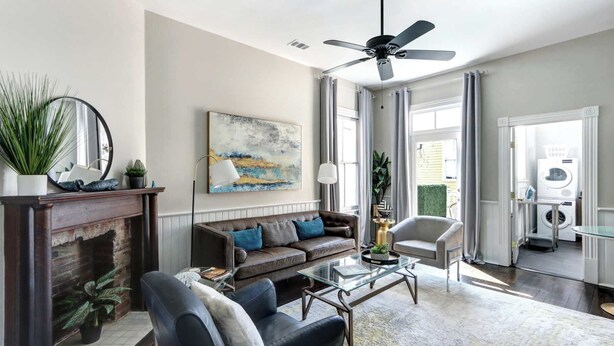 A spacious living room with a fireplace, a sofa, a coffee table, and a ceiling fan. - The Whale Loft | Historic Charm + Balcony (Savannah)