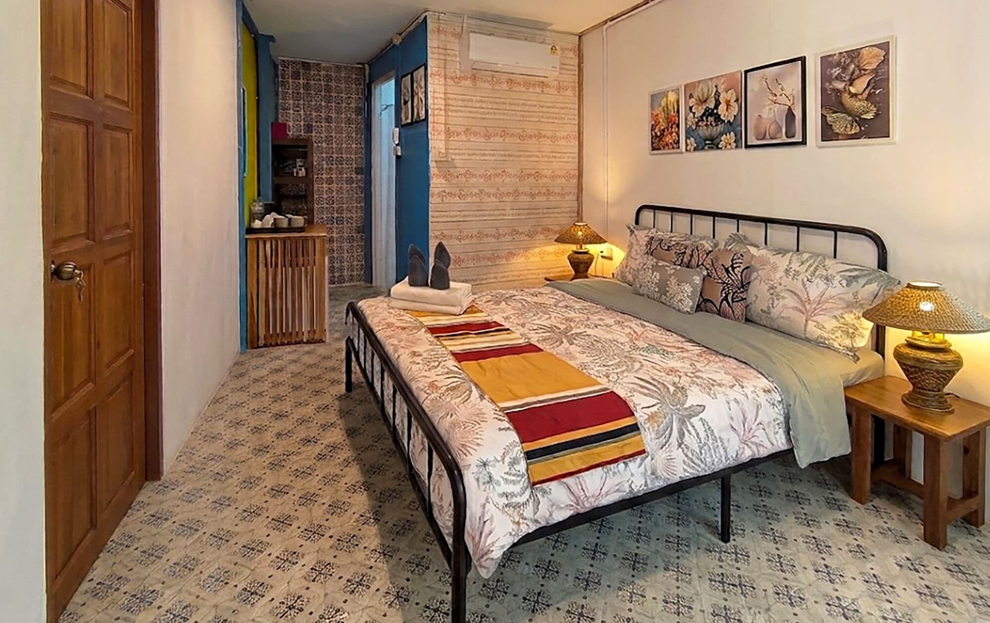 A bedroom with a bed, bedside lamps, a bedside table, a wardrobe, and a door.