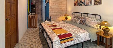 A bedroom with a bed, bedside lamps, a bedside table, a wardrobe, and a door.