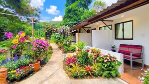 Un sendero en un jardín que lleva a un edificio, con una banca y una mesa.