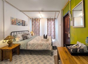 Un dormitorio con cama, mesitas de noche, lámpara, espejo y puerta.