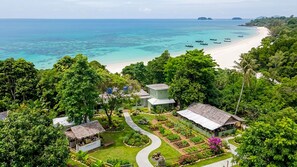 Un resort tropical con vistas a la playa, una zona ajardinada y varios edificios.