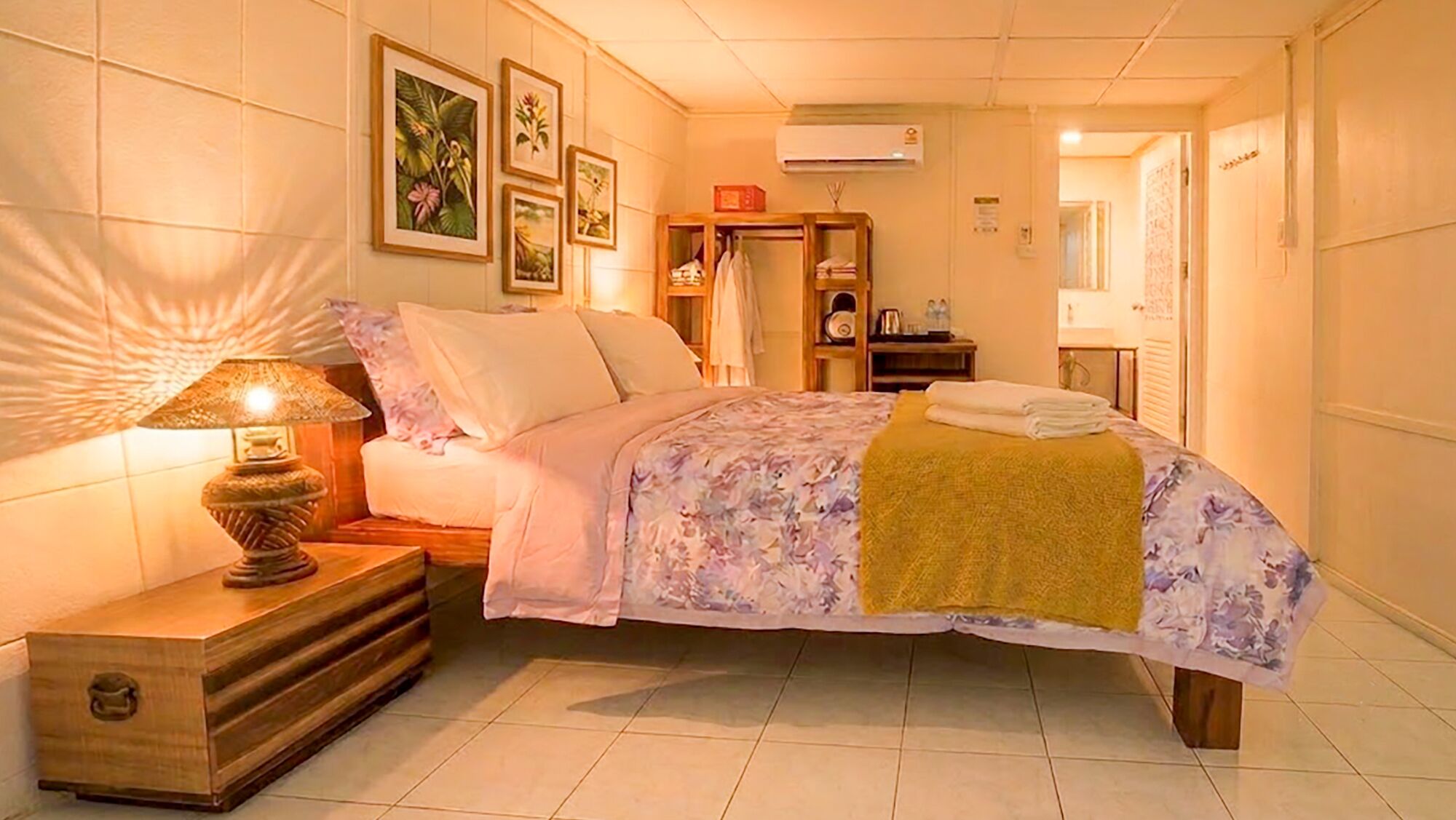 Ein Hotelzimmer mit einem Bett, einem Nachttisch, einer Lampe, einem Kleiderschrank und einem Badezimmer im Hintergrund.