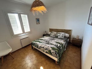 Une chambre à coucher avec un lit, une chaise, une fenêtre et un radiateur.