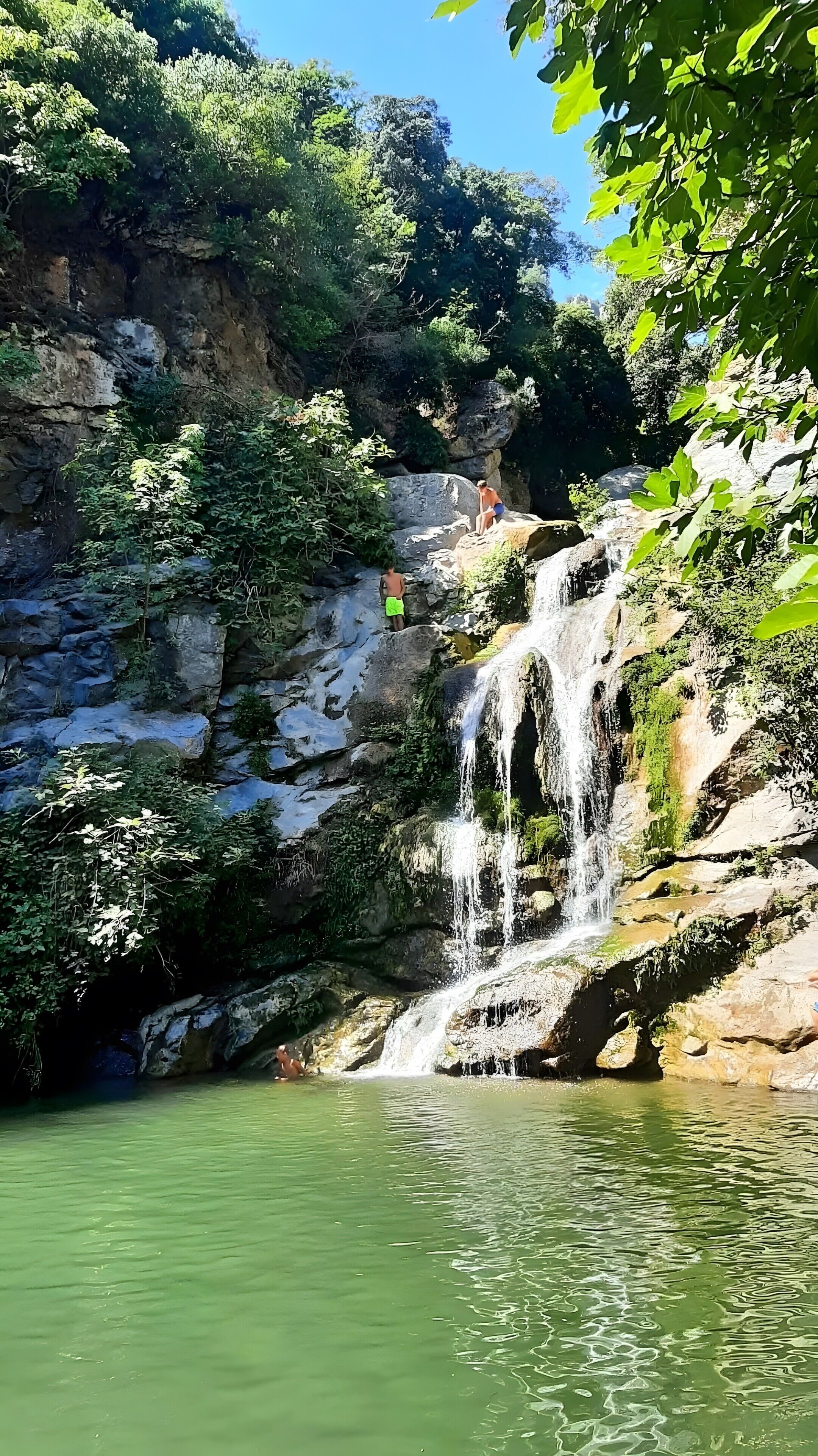 Una cascada natural, terreno rocoso y una masa de agua.