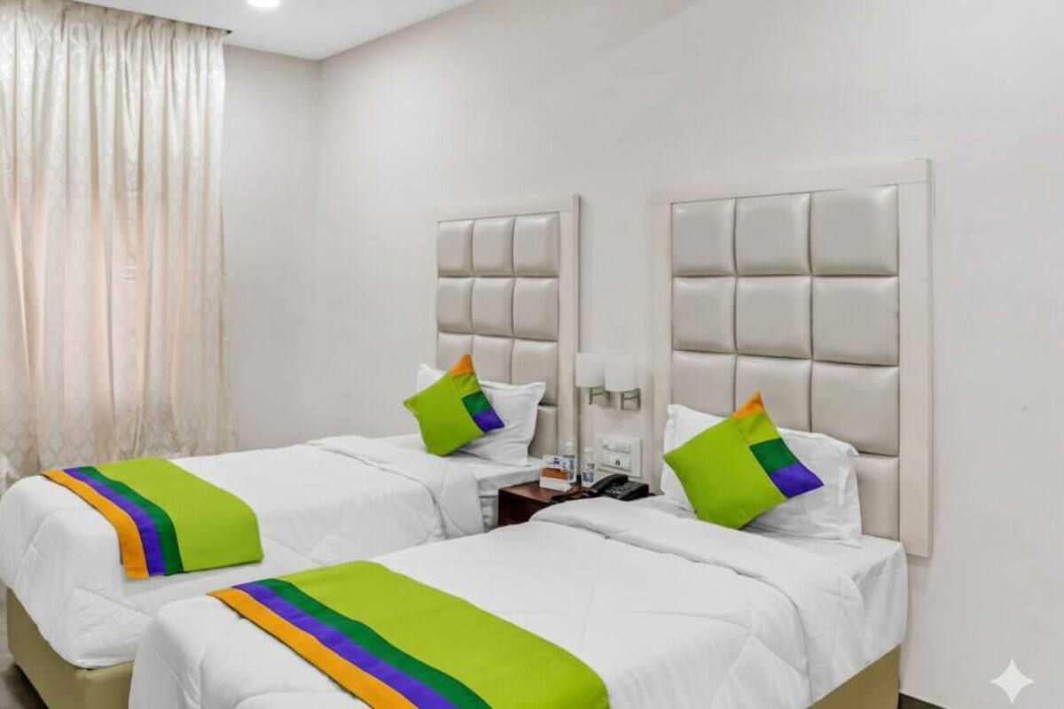 A hotel room with two beds, each with a headboard, white bedding, and colorful throw pillows.