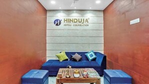 Una zona de recepción con un sofá azul, una mesa de centro y un ventilador de techo.