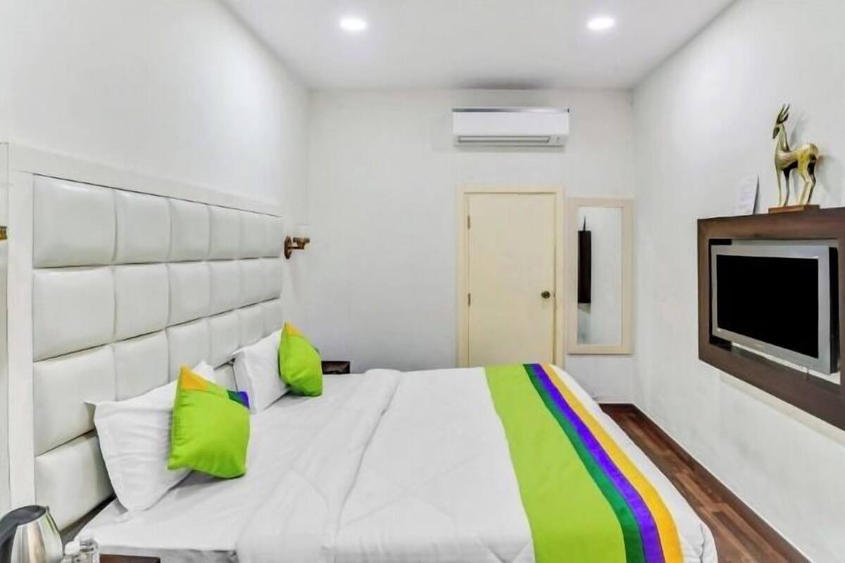 A hotel room with a bed, a TV mounted on the wall, and a door.
