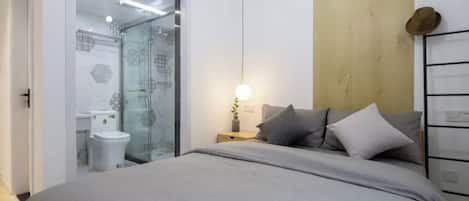 A modern bedroom with a bed, bedside table, and a nightstand.